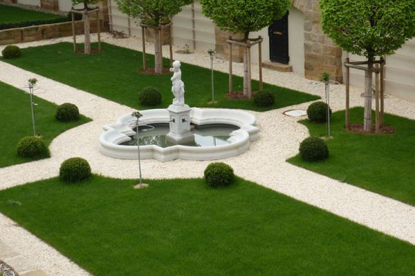 Professionell gestalteter Ziergarten mit Brunnen, Kieswegen und Formschnittgehölzen