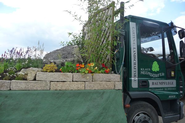 Firmenfahrzeug von Klaus Neundörfer Garten- und Landschaftsbau mit bepflanztem Natursteinbeet