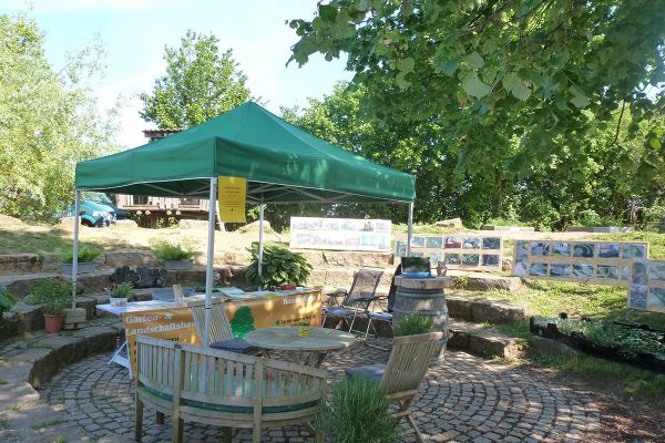 Infostand von Galabau Neundörfer in einer parkähnlichen Umgebung mit Naturstein und Bepflanzung